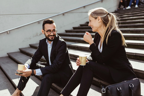 A businesswoman and a businessman are smiling and talking about temporary work